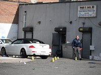 Evidence markers highlight where shell casings and other evidence are discovered by a white vehicle where a 35-year-old man is killed after...