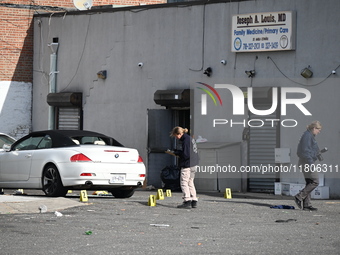 Evidence markers highlight where shell casings and other evidence are discovered by a white vehicle where a 35-year-old man is killed after...