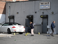 Evidence markers highlight where shell casings and other evidence are discovered by a white vehicle where a 35-year-old man is killed after...