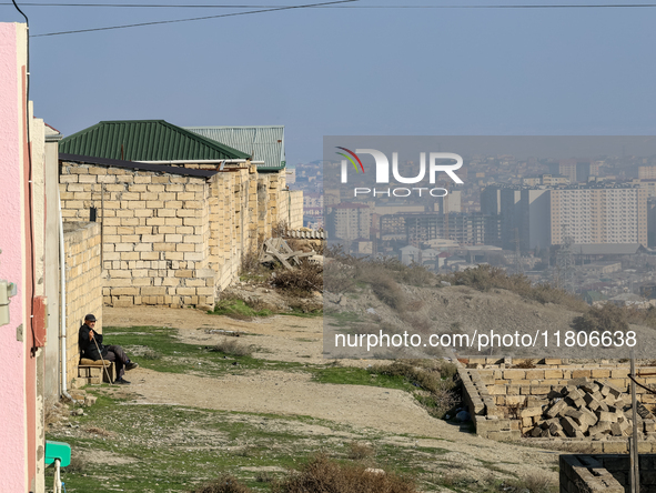 An elderly man sits on a bench in the suburbs of Baku, capital of Azerbaijan on November 24, 2024. 