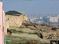 An elderly man sits on a bench in the suburbs of Baku, capital of Azerbaijan on November 24, 2024. (