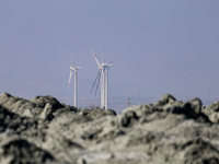 Power windmills are seen behind an austere, harsh landscape of dry mud left on mud volcano in Gobustan region near Baku, Azerbaijan on Novem...