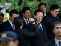 Lee Jae-myung (center), leader of the Democratic Party of Korea, waves to his supporters as he leaves the Seoul Central District Court in Se...