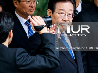 Lee Jae-myung (center), leader of the Democratic Party of Korea, waves to his supporters as he leaves the Seoul Central District Court in Se...