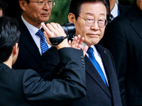 Lee Jae-myung (center), leader of the Democratic Party of Korea, waves to his supporters as he leaves the Seoul Central District Court in Se...