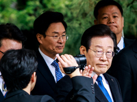 Lee Jae-myung (center), leader of the Democratic Party of Korea, waves to his supporters as he leaves the Seoul Central District Court in Se...