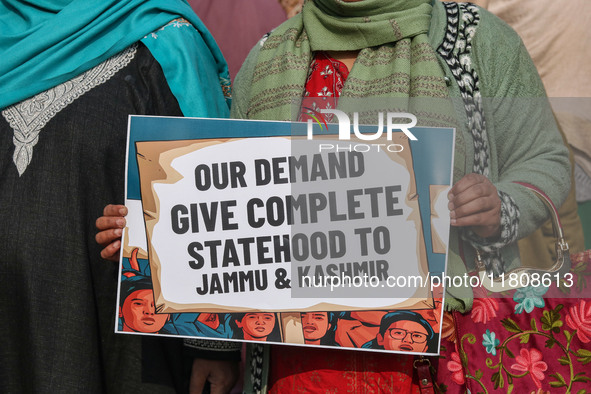 A female worker of the Jammu and Kashmir Pradesh Congress Committee (JKPCC) holds a placard during a protest demanding the restoration of st...