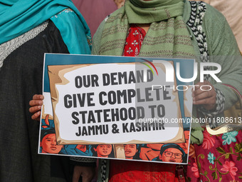 A female worker of the Jammu and Kashmir Pradesh Congress Committee (JKPCC) holds a placard during a protest demanding the restoration of st...