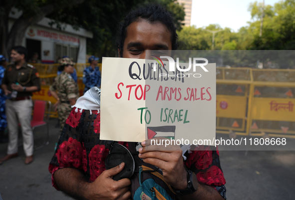 A member of the LGBT community holds a placard demanding an end to the arms sale to Israel at the pride march in New Delhi, India, on Novemb...