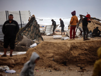 Palestinian displaced persons inspect their tents, which are damaged by wind and rain after heavy rainfall in Deir al-Balah, central Gaza St...