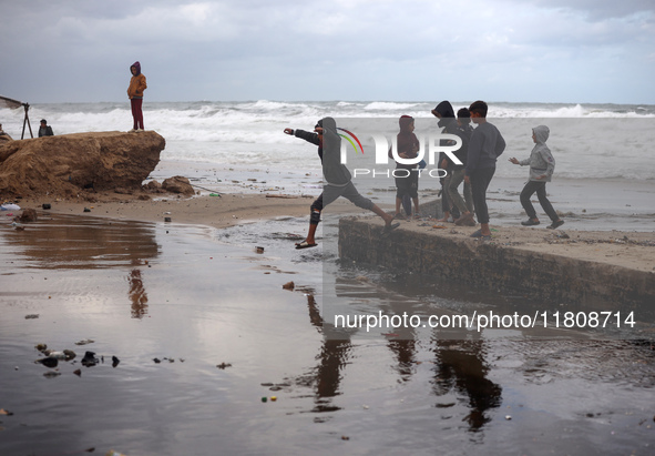 Displaced Palestinian boys walk along the seashore outside their tents, which are damaged by wind and rain following heavy rainfall in Deir...