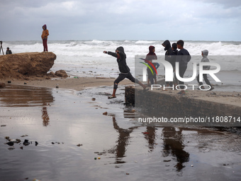 Displaced Palestinian boys walk along the seashore outside their tents, which are damaged by wind and rain following heavy rainfall in Deir...