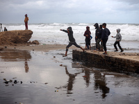 Displaced Palestinian boys walk along the seashore outside their tents, which are damaged by wind and rain following heavy rainfall in Deir...