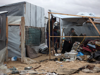 Palestinian displaced persons inspect their tents, which are damaged by wind and rain after heavy rainfall in Deir al-Balah, central Gaza St...