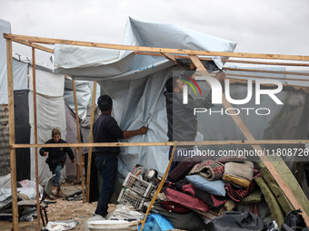 Palestinian displaced persons inspect their tents, which are damaged by wind and rain after heavy rainfall in Deir al-Balah, central Gaza St...