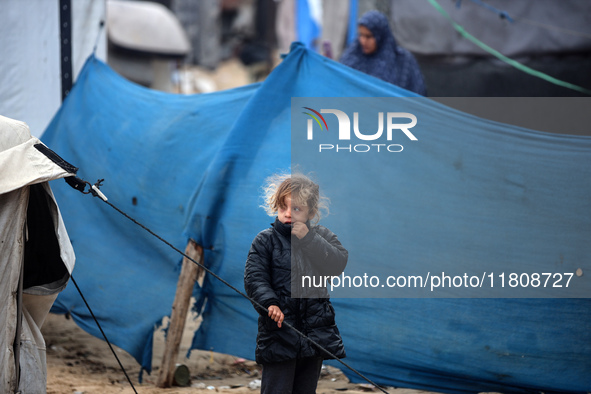 A displaced Palestinian girl stands in front of her family's tent, which is damaged by wind and rain after heavy rainfall in Deir al-Balah,...