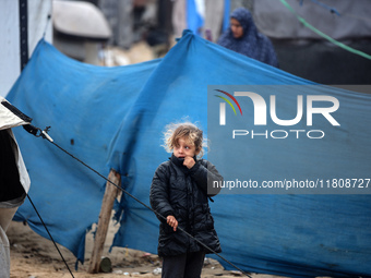 A displaced Palestinian girl stands in front of her family's tent, which is damaged by wind and rain after heavy rainfall in Deir al-Balah,...