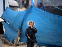 A displaced Palestinian girl stands in front of her family's tent, which is damaged by wind and rain after heavy rainfall in Deir al-Balah,...