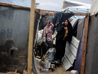 Palestinian displaced persons inspect their tents, which are damaged by wind and rain after heavy rainfall in Deir al-Balah, central Gaza St...