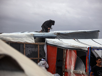 Palestinian displaced persons inspect their tents, which are damaged by wind and rain after heavy rainfall in Deir al-Balah, central Gaza St...