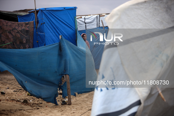 A displaced Palestinian girl stands in front of her family's tent, which is damaged by wind and rain after heavy rainfall in Deir al-Balah,...