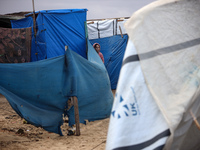 A displaced Palestinian girl stands in front of her family's tent, which is damaged by wind and rain after heavy rainfall in Deir al-Balah,...