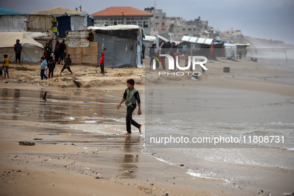 Displaced Palestinian boys walk along the seashore outside their tents, which are damaged by wind and rain following heavy rainfall in Deir...