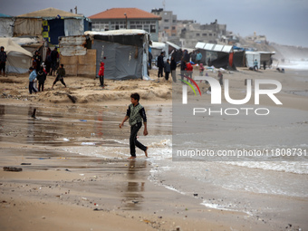 Displaced Palestinian boys walk along the seashore outside their tents, which are damaged by wind and rain following heavy rainfall in Deir...