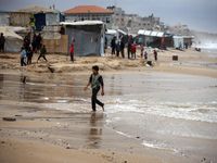 Displaced Palestinian boys walk along the seashore outside their tents, which are damaged by wind and rain following heavy rainfall in Deir...