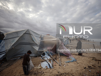 Palestinian displaced persons inspect their tents, which are damaged by wind and rain after heavy rainfall in Deir al-Balah, central Gaza St...