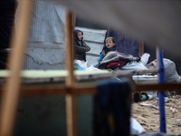 Palestinian displaced persons inspect their tents, which are damaged by wind and rain after heavy rainfall in Deir al-Balah, central Gaza St...