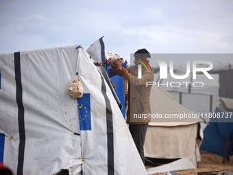 Palestinian displaced persons inspect their tents, which are damaged by wind and rain after heavy rainfall in Deir al-Balah, central Gaza St...