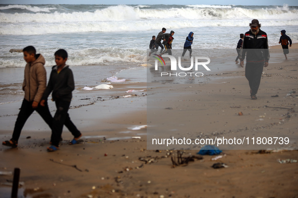 Displaced Palestinian boys walk along the seashore outside their tents, which are damaged by wind and rain following heavy rainfall in Deir...