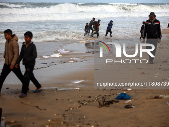 Displaced Palestinian boys walk along the seashore outside their tents, which are damaged by wind and rain following heavy rainfall in Deir...