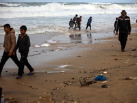 Displaced Palestinian boys walk along the seashore outside their tents, which are damaged by wind and rain following heavy rainfall in Deir...