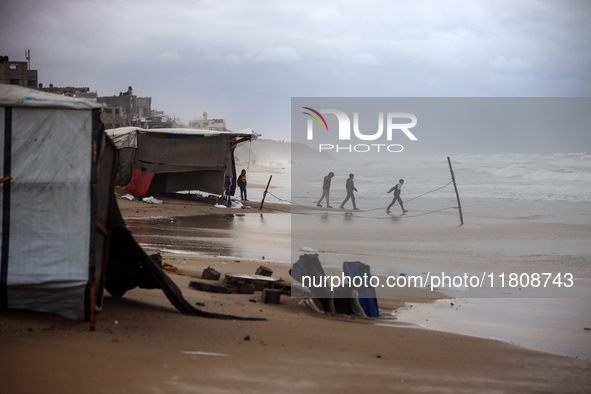 Displaced Palestinian boys walk along the seashore outside their tents, which are damaged by wind and rain following heavy rainfall in Deir...