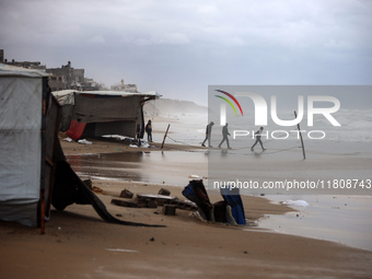 Displaced Palestinian boys walk along the seashore outside their tents, which are damaged by wind and rain following heavy rainfall in Deir...