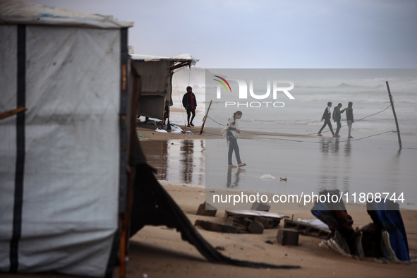 Displaced Palestinian boys walk along the seashore outside their tents, which are damaged by wind and rain following heavy rainfall in Deir...