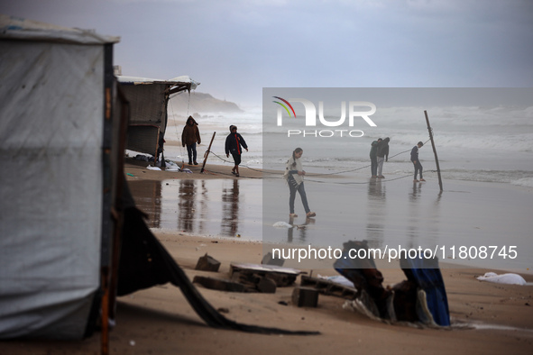 Displaced Palestinian boys walk along the seashore outside their tents, which are damaged by wind and rain following heavy rainfall in Deir...