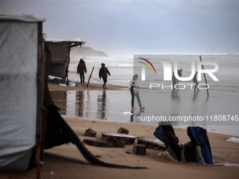 Displaced Palestinian boys walk along the seashore outside their tents, which are damaged by wind and rain following heavy rainfall in Deir...