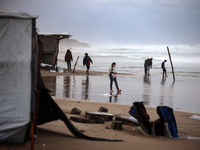 Displaced Palestinian boys walk along the seashore outside their tents, which are damaged by wind and rain following heavy rainfall in Deir...