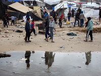 Palestinian displaced persons inspect their tents, which are damaged by wind and rain after heavy rainfall in Deir al-Balah, central Gaza St...