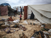 Palestinian displaced persons inspect their tents, which are damaged by wind and rain after heavy rainfall in Deir al-Balah, central Gaza St...