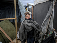 A displaced Palestinian boy carries a blanket in front of his family's tent, which is damaged by wind and rain following heavy rainfall in D...