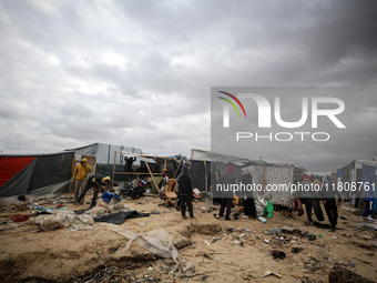 Palestinian displaced persons inspect their tents, which are damaged by wind and rain after heavy rainfall in Deir al-Balah, central Gaza St...