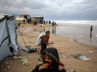 Palestinian displaced persons inspect their tents, which are damaged by wind and rain after heavy rainfall in Deir al-Balah, central Gaza St...