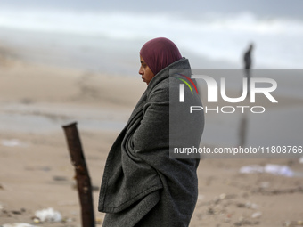 A displaced Palestinian woman stands outside her tent, which is damaged by wind and rain following heavy rainfall in Deir al-Balah, central...