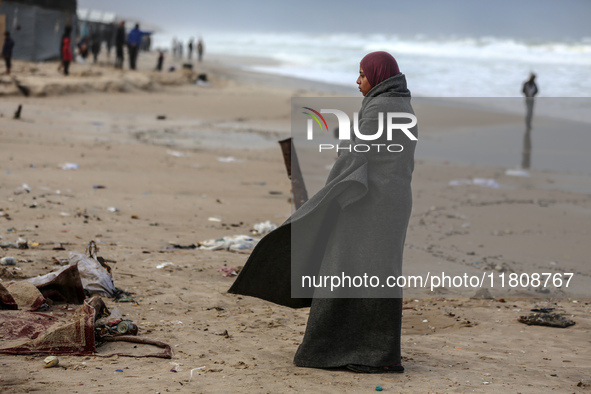 A displaced Palestinian woman stands outside her tent, which is damaged by wind and rain following heavy rainfall in Deir al-Balah, central...