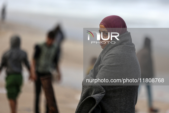 A displaced Palestinian woman stands outside her tent, which is damaged by wind and rain following heavy rainfall in Deir al-Balah, central...