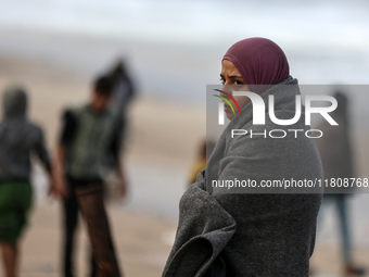 A displaced Palestinian woman stands outside her tent, which is damaged by wind and rain following heavy rainfall in Deir al-Balah, central...